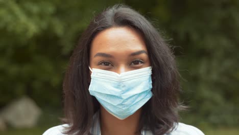 Portrait-Of-Pretty-Girl-Smiling-With-Medical-Face-Mask-On-Outdoors,-Looking-At-Camera,-Close-Up-Shot