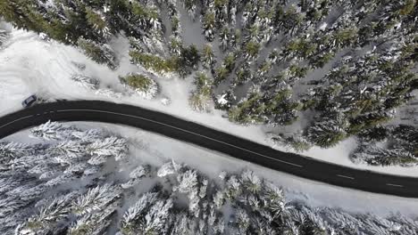 Curvy-windy-road-in-snow-covered-forest,-top-down-aerial-view-2