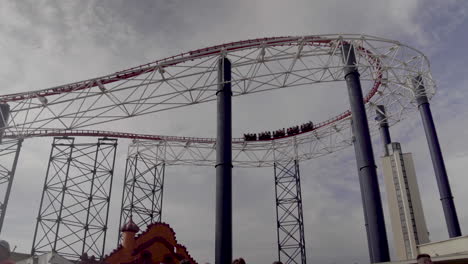 4K-rollercoaster-speeding-around-corner-high-above-theme-park-in-UK
