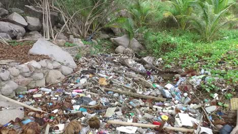Massive-man-made-trash-littered-jungle-near-the-beach,-backwards-moving-drone