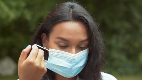 Portrait-of-a-Beautiful-Dark-Haired-Young-Woman-Taking-Off-Protective-Medical-Face-Mask-Then-Smile