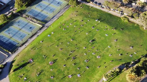 Drone-of-San-Francisco-park-with-6-foot-circles-painted-for-social-distancing-with-zoom-to-skyline