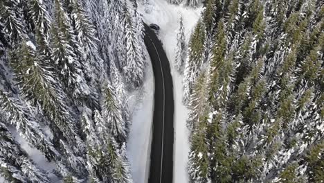 Curvy-windy-road-in-snow-covered-forest,-top-down-aerial-view-1
