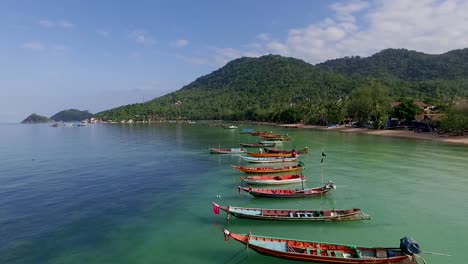 Slowly-Fly-over-longtail-boats-on-empty-beach-at-close-up-Thailand