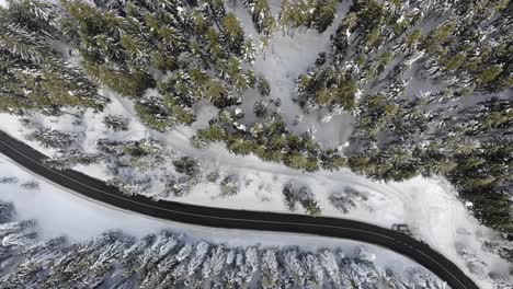 Curvy-windy-road-in-snow-covered-forest,-top-down-aerial-view-7