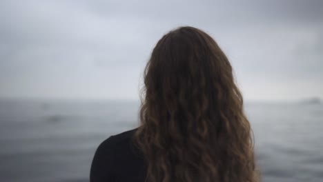 Brunette-Girl-Move-Curly-Hair-With-Ocean-In-The-Background