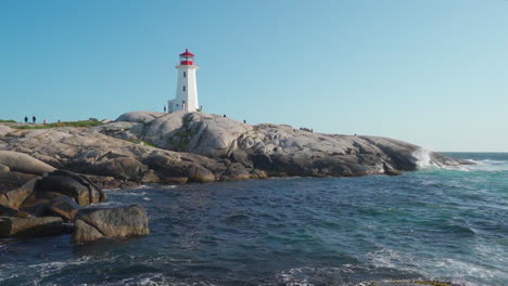 Lighthouse-at-Peggy's-Cove,-Nova-Scotia,-Canada-during-golden-hour,-with-tourists