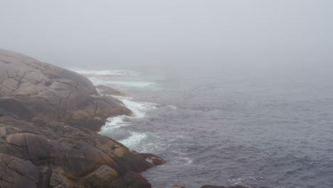 A-coastal-foggy-moody-coastal-morning-in-Nova-Scotia,-Canada-with-waves-of-the-ocean-crashing