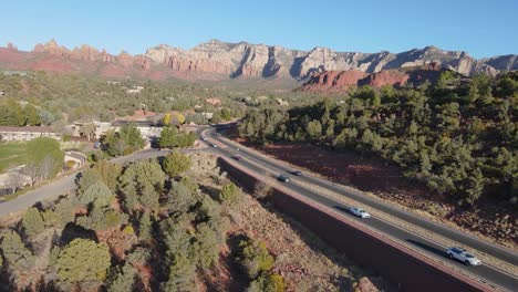 Highway-in-Arizona-near-Sedona,-red-rocks-on-horizon,-road-trip-USA
