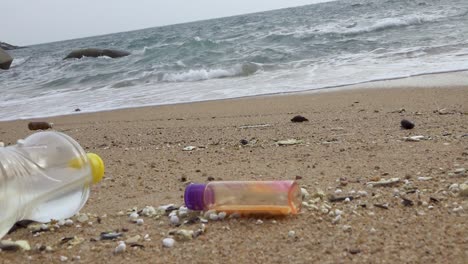 Various-of-littered-bottle-trash-dumped-on-beachfront,-horizontal-zoom-out-shot