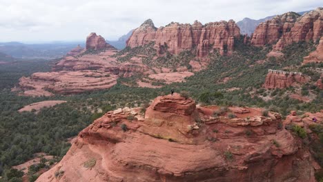 Aerial-approaching-man-on-top-of-red-rocks-formations,-Sedona,-Arizona