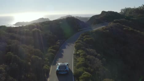 Aerial,-BMW-i8-hybrid-car-driving-coastal-road-in-Marin-Headlands,-California