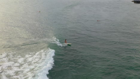 Aerial-view-of-a-surfer-riding-a-surfboard-on-a-wave-in-a-warm-climate