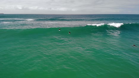 Aerial-drone-view-of-a-surfers-in-waves,-cloudy-New-south-Wales,-Australia