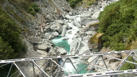 Pequeño-Puente-Que-Cruza-El-Flujo-Del-Río-Glacial-Azul-Rocoso