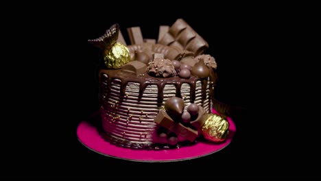 Schokoladenkuchen,-Der-Sich-Von-Einer-Silhouette-Vor-Einem-Dunklen-Hintergrund-Bis-Zur-Vollständigen-Beleuchtung-Mit-Pralinen-Zeigt,-Die-Oben-Und-An-Den-Seiten-Dieses-Zweistöckigen-Kuchens-Liegen