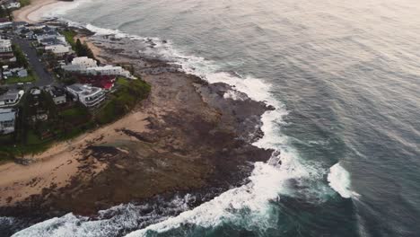 Drone-pan-shot-over-coastal-homes-and-ocean-waves-at-reef-beach-in-Blue-Bay-The-Entrance-Central-Coast-NSW-Australia-3840x2160-4K