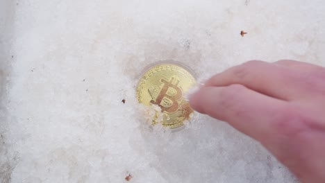 Männliche-Hand,-Die-Goldenes-Bitcoin-Aus-Dem-Schnee-Gräbt-1