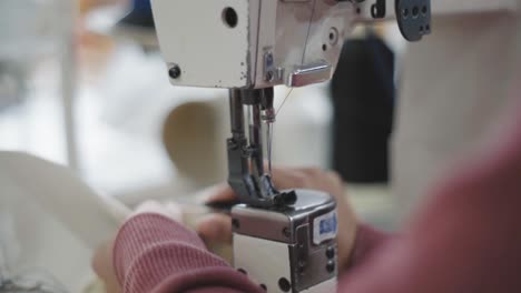 Close-up-of-workers-hands-using-a-industrial-sewing-mach-to-sew-cream-leather