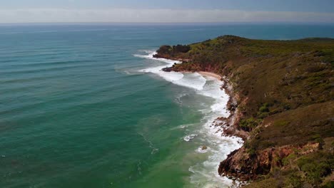 Aerial-drone-view-over-waves-hitting-the-coast-of-Evans-Head,-in-sunny-Australia