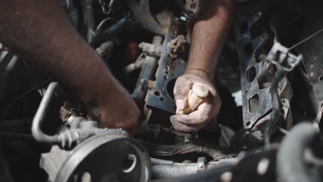 Closeup-of-hands-working-with-hand-tools-on-an-oily-dirty-engine,-inside-workshop