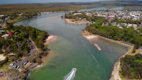 Aerial-drone-view-of-a-boat-turning-on-a-Evans-river,-sunny-day,-in-Australia