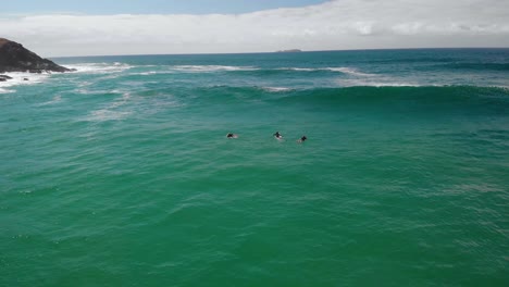 Aerial-view-of-surfers-waiting-for-big-waves,-in-Australia---reverse,-drone-shot