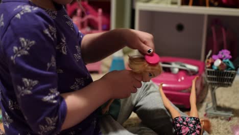 4-Jahre-Altes-Mädchen-Bürstet-Das-Haar-Einer-Puppe-Mit-Einer-Winzigen-Rosa-Bürste-Mit-Vielen-Spielsachen-Im-Hintergrund