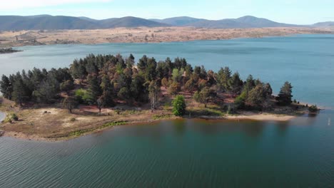 Aerial-view-towards-the-Lion-island-at-lake-Jindabyne,-sunny-day,-in-Australia---tilt,-drone-shot