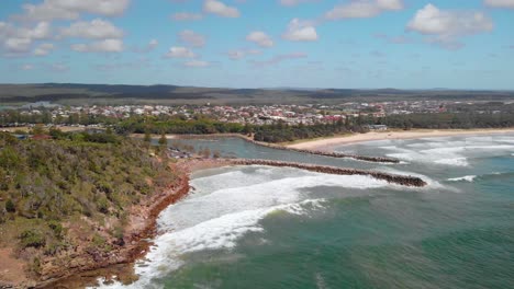 Aerial-view-away-from-waves-hitting-the-shore-of-the-Evans-Head-village,-sunny,-summer-day,-in-Australia---reverse,-drone-shot