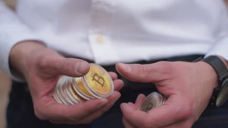 Slow-Motion-Of-Young-Professional-Businessman-Counting-Physical-Golden-Bitcoin-In-His-Hands