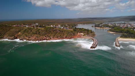 Aerial-view-over-waves-crashing-the-coastline-of-the-Evans-Head-town,-sunny-day---tracking,-pan,-drone-shot