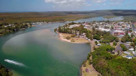 Aerial-view-overlooking-a-boat-on-a-river,-at-the-Evans-Head-village,-New-South-Wales,-Australia---reverse,-drone-shot