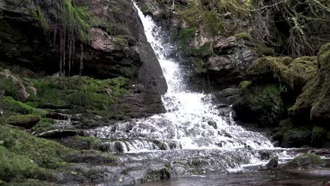 4K-small-waterfall-flowing-over-rocks-in-forest,-South-Wales,-UK