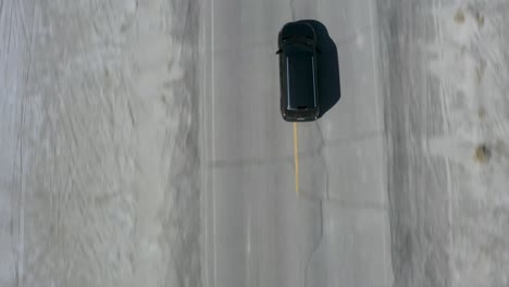 Overhead-Aerial-Tilt-up-View-of-Car-Driving-on-Vast-Open-Desert-Road