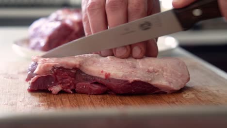 Chef-preparing-piece-of-lamb-meat-for-cooking