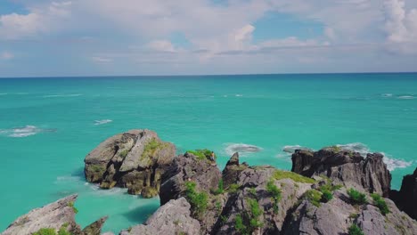 Bermuda-drone-shot-of-Horseshoe-Bay-with-people-climbing-the-rock-formations-and-a-view-out-to-sea