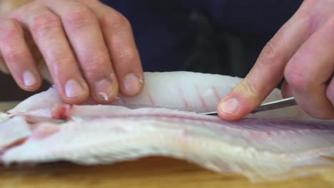 Sliding-knife-through-fish-to-separate-fillets