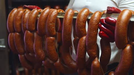 The-butcher-shows-a-juicy-and-tasty-production-of-real-meat-sausages,-pulled-out-of-the-smokehouse
