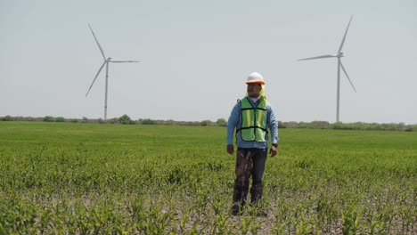 Trabajador-Caminando-En-Un-Campo-Frente-A-Turbinas-De-Una-Granja-De-Energía-Eólica,-México