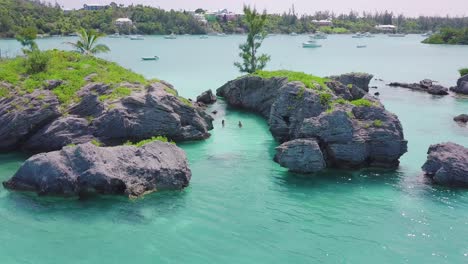 Bermuda-low-drone-shot-of-two-swimmers-floating-in-clear-shallow-water-near-Morgan's-Island