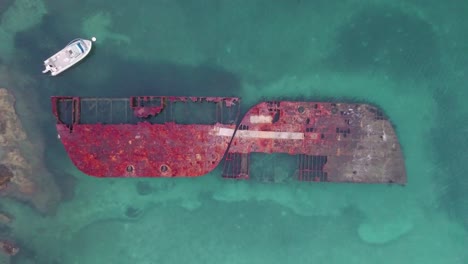 Bermuda-rising-drone-shot-of-a-rusted-shipwreck-in-the-shallow-turquoise-water-of-Stovell-Bay
