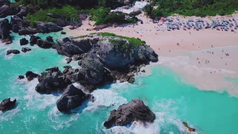 Bermuda-drone-shot-of-Horseshoe-Bay-Cove-rock-formations,-turquoise-water-tourists-in-shallow-water