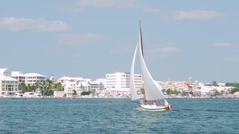 Bermudas,-Hamilton-Harbour,-Velero-Llegando-Al-Muelle,-Con-El-Horizonte-De-La-Ciudad-Al-Fondo