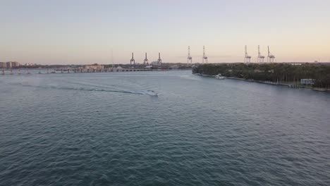 Aerial-shot-of-motorboat-against-port-cranes,-Miami,-Florida