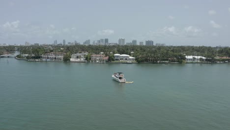 Luxury-cruiser-yacht-on-Biscayne-Bay-against-waterfront-mansions,-Miami,-Florida