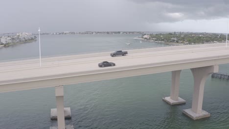 Porsche-911-Carrera-drives-on-bridge-in-St-Pete-Beach,-Florida,-USA,-aerial-view