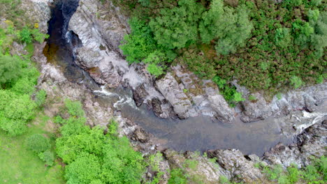 Top-down-drone-video-of-a-river-flowing-through-a-tree-lined-gorge-with-waterfalls