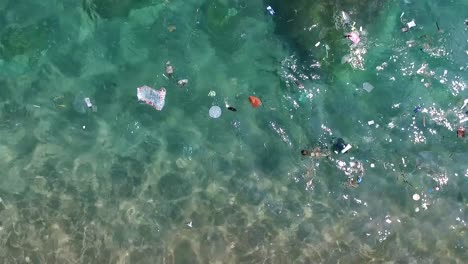 Rubbish-float-in-the-water-near-the-beach-and-corals-steady-shoot-from-above-1080-HD-Asia,-Thailand-Filmed-with-Sony-AX700