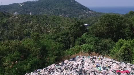 Drone-fly-forward-above-a-mountain-of-trash-between-trees-Island-background-1080-HD-Asia,-Thailand-Filmed-with-Sony-AX700